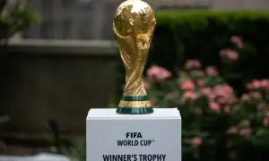 Złoty Puchar Świata FIFA, marzenie każdego z gospodarzy mistrzostw świata w piłce nożnej, lśni na tle zieleni i różowych kwiatów.