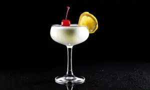 En elegant drink, en "white lady", med körsbär och citronskiva på svart bakgrund.