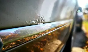 Nahaufnahme von Rostblasen am Auto, die eine Rostbehandlung am Auto erfordern.