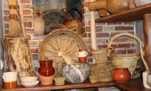 Vasi in terracotta, cesti intrecciati e scope di paglia evocano antiche attività artigianali.