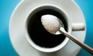 Cuillère de sucre au-dessus d'une tasse de café noir. Une image pour illustrer l'arrêter le sucre effet.