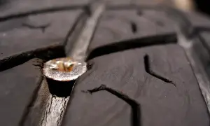 Une mèche est plantée dans le pneu d'une voiture, causant une crevaison.