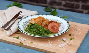 Tallrik med stuvad spenat, stekt korv och potatisklyftor. En klassisk svensk måltid.