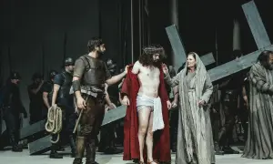 Szene aus einem Passionsspiel: Jesus mit Dornenkrone, umgeben von Soldaten und Frauen, die ein Kreuz tragen.