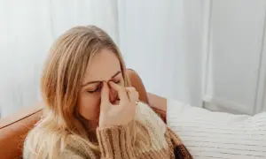 Kobieta z zamkniętymi oczami masuje nasadę nosa, co może być jednym z objawów miastenii.