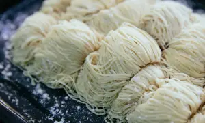 Des portions de pâtes crues, fines et blanches, sont disposées sur un plateau. Une question se pose : peut-on congeler des pâtes cuites ?