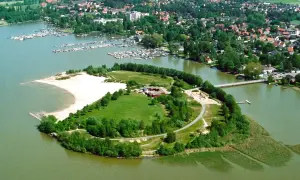 Grüne Insel mit Sandstrand und Gebäuden im Steinhuder Meer, umgeben von einem Yachthafen und einer Ortschaft.