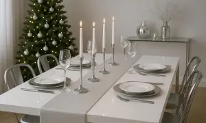 Elegancki stół wigilijny biało srebrny, ozdobiony świecami i choinką, czeka na gości.