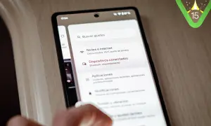 Mano interactuando con un teléfono que muestra la configuración de Android 15. El logo de Android 15 aparece en la esquina superior derecha.