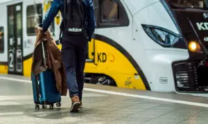 Podróżny z walizką i kurtką zmierza na peron, gdzie czeka łódź Władysławowo.