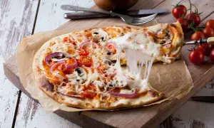 Eine köstliche Pizza mit geschmolzenem Käse, Tomaten, Zwiebeln und Pilzen. Der Teig, wie vom echten Italiener, wurde im Thermomix zubereitet.