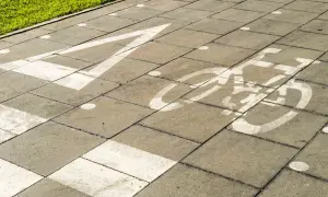 Un carril bici pintado sobre un **damero carretera** de baldosas grises. Una flecha blanca indica la dirección, seguida por el símbolo de una bicicleta.