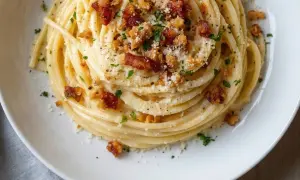 Un plat de tagliatelles carbonara crémeuses, garni de lardons croustillants, de parmesan râpé et de persil frais. Un délice italien.