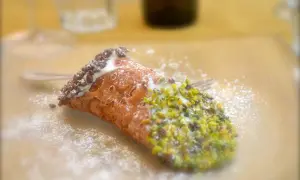En krispig cannelloni dessert med pistagenötter och chokladströssel, pudrad med florsocker.