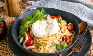 Spaghetti mit Burrata, Kirschtomaten und Basilikum in einer Schüssel.