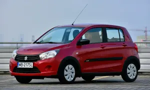 Czerwony Suzuki Celerio z kierowcą za kierownicą, zaparkowany na zewnątrz.