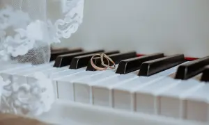 Dwa obrączki na klawiszach pianina, obok białej koronki. Gotowa lista utworów do ZAIKS wesele.