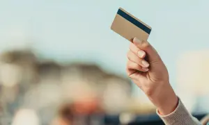 Dłoń trzyma złotą kartę Mastercard debit fx.