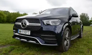 Ciemnoniebieski Mercedes GLE 450 stoi na trawie, z przodem skierowanym w stronę widza.