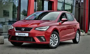 Czerwony SEAT Ibiza, jeden z popularnych modele, zaparkowany przed salonem samochodowym.