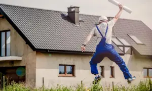 Un trabajador salta de alegría frente a una casa con tejas, celebrando la elección de los tipos de cubiertas perfectos.
