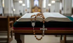 Otwarta księga i różaniec na ławce w kościele. Poniedziałkowe tajemnice różańca czekają na rozważenie.