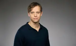 David Pålsson, en ung man med blå ögon och brunt hår, bär en mörkblå pikétröja.