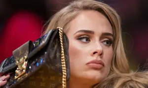 Adele z torebką na koncercie, zamyślona, z makijażem i blond włosami.