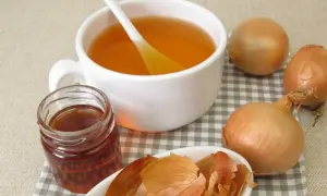 Naturalny wywar z łupin cebuli, miód i świeże cebule. Napar o bursztynowym kolorze w białej filiżance.