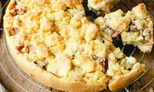 Ein köstlicher Rhabarberkuchen mit Streuseln, der auf einem Gitter abkühlt. Die süßen Streusel bedecken die saftige Rhabarberfüllung.