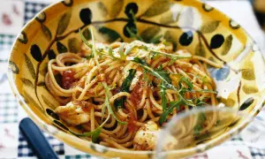 En skål med spaghetti med tomatsås, toppad med ruccola och strödd med svartpeppar. En härlig pasta med tomatsås som ser utsökt ut.