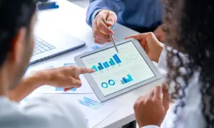 Zespół analizuje dane na tablecie, dyskutując o wynikach. Chcesz wiedzieć, jak sprawdzić czy jest się w BIK?