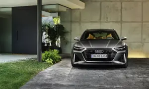 Szary Audi RS6 Avant z beżowym wnętrzem zaparkowany przed nowoczesnym domem. Sprawdź audi rs6 cena.