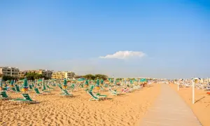 Piękna plaża w Bibione, pełna leżaków i parasoli, zaprasza do relaksu. Liczne atrakcje czekają na turystów.