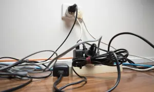 Un enchevêtrement de fils électriques branchés sur une multiprise et une prise murale. Un vrai défi pour faire de l'électricité soi-même sans s'emmêler !