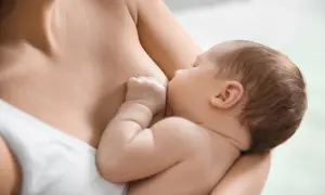 Dziecko karmione piersią. Wskazówki, jak rozpoznać brak pokarmu w piersiach, gdy maluch jest przytulony do mamy.