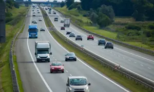 Na autostradzie ruch samochodów. Niebieska ciężarówka wykonuje wyprzedzanie z prawej strony, omijając inne pojazdy.