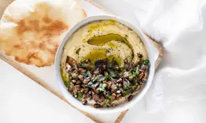 Un bol de caviar d'aubergine libanais, garni d'huile d'olive et de persil, servi avec du pain pita. Une recette savoureuse à découvrir.