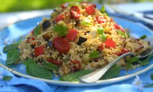 Piatto colorato di cous cous integrale con verdure miste, pomodorini e basilico. Un'idea gustosa per le tue cous cous integrale ricette.