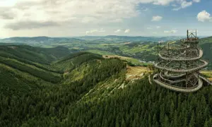 Widok na Sky Walk w Czechach, spiralną wieżę widokową pośród zielonych lasów i pagórków.