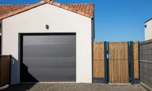 Nowa, nowoczesna brama wjazdowa z drewna i metalu, obok garażu.