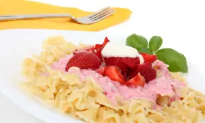 Makaron z truskawkami i kremowym sosem, udekorowany listkiem bazylii. Pyszne danie, które zaskoczy smakiem.