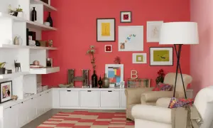 Gemütliches Wohnzimmer mit koral farbener Wand, weißen Regalen, Kunstwerken und einem beigen Sessel.
