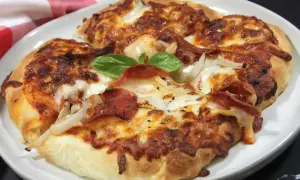 Pyszna pizza z air fryera, z ciągnącym się serem, pepperoni i cebulą, ozdobiona listkiem bazylii.