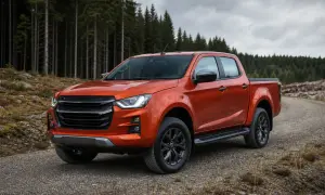 Orange pickup står på grusväg framför en tät granskog.