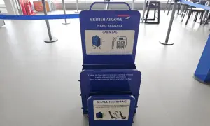 Niebieska miarka bagażu podręcznego British Airways na lotnisku. Sprawdź, czy Twój bagaż podręczny zmieści się w wyznaczonych wymiarach.
