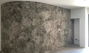 Parete curva con un suggestivo intonaco a calce decorato con motivi floreali e geometrici in stile damascato.