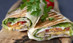 Pyszna tortilla z jajkiem, serem, warzywami i kurczakiem, podana na desce.