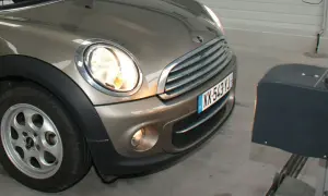 Réglage des feux diurnes d'une Mini Cooper marron, avec un appareil de mesure à droite.