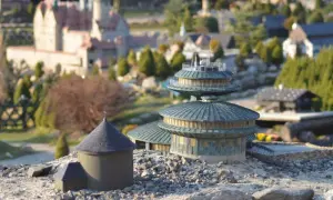Miniaturowe budowle, w tym okrągły budynek z kopułą i wielopoziomowa konstrukcja, tworzą krajobraz jednego z parków miniatur w Polsce.